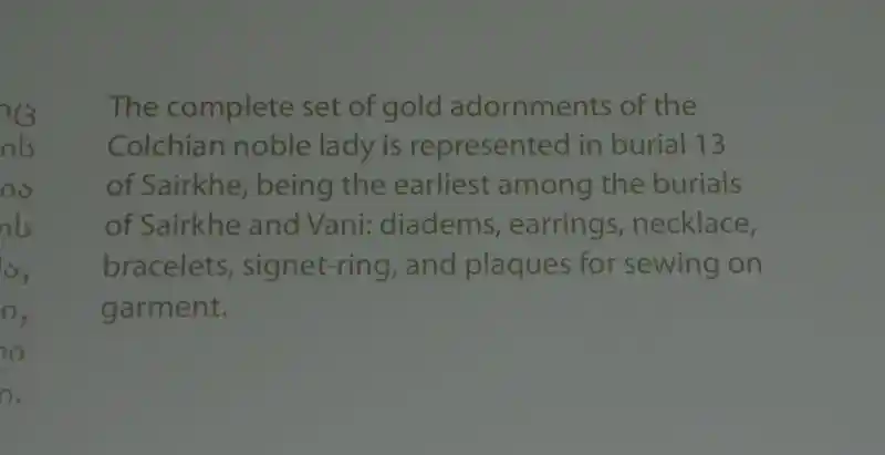 A gold necklace with red and gold beads and bullhead pendant